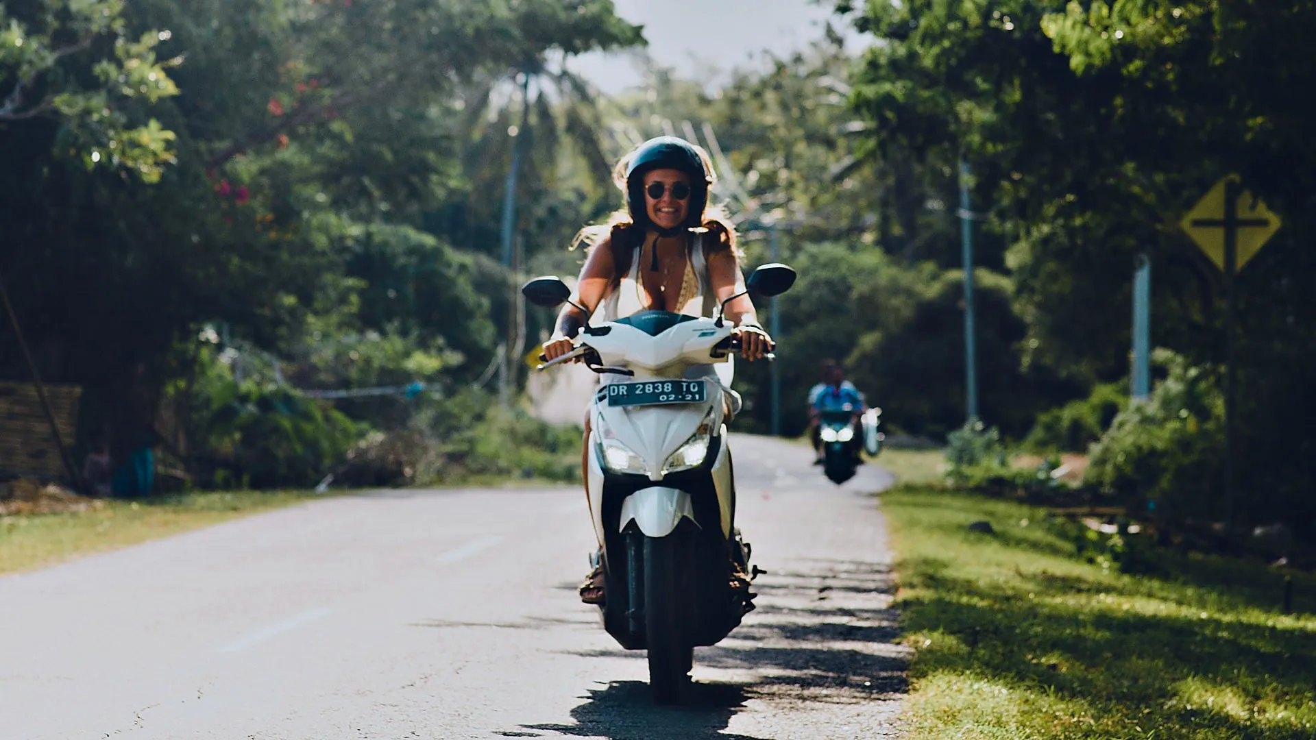 Student riding a scooter on a road in Bali