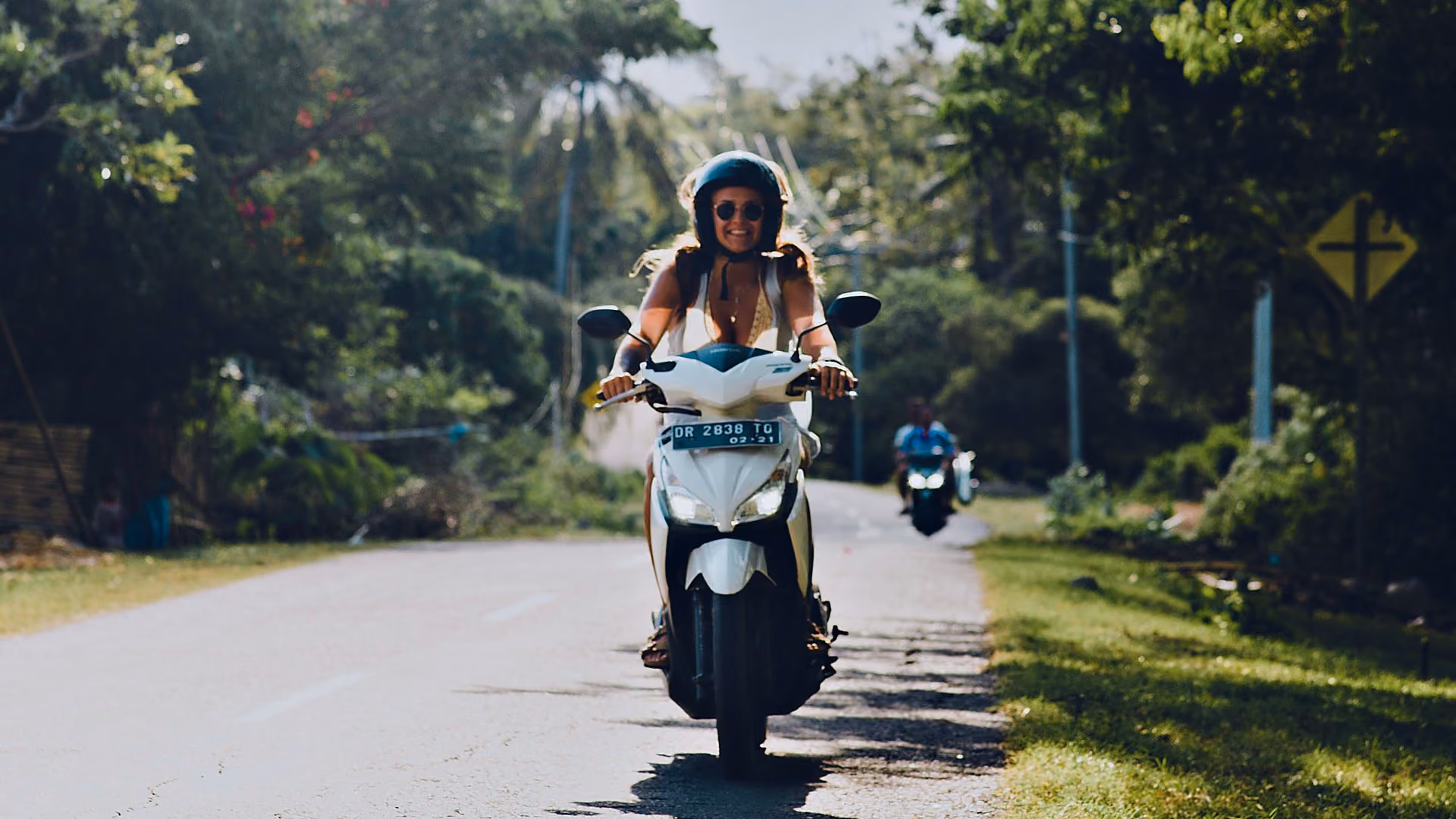 Student riding a scooter on a road in Bali