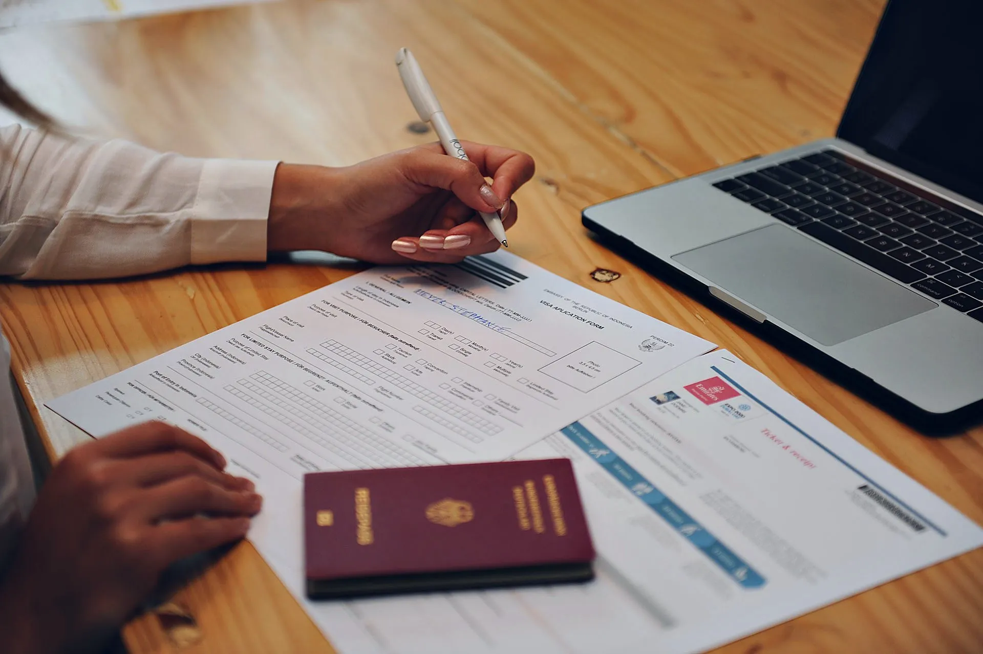 Student filling in visa documents for studying in Bali, with a passport on the table