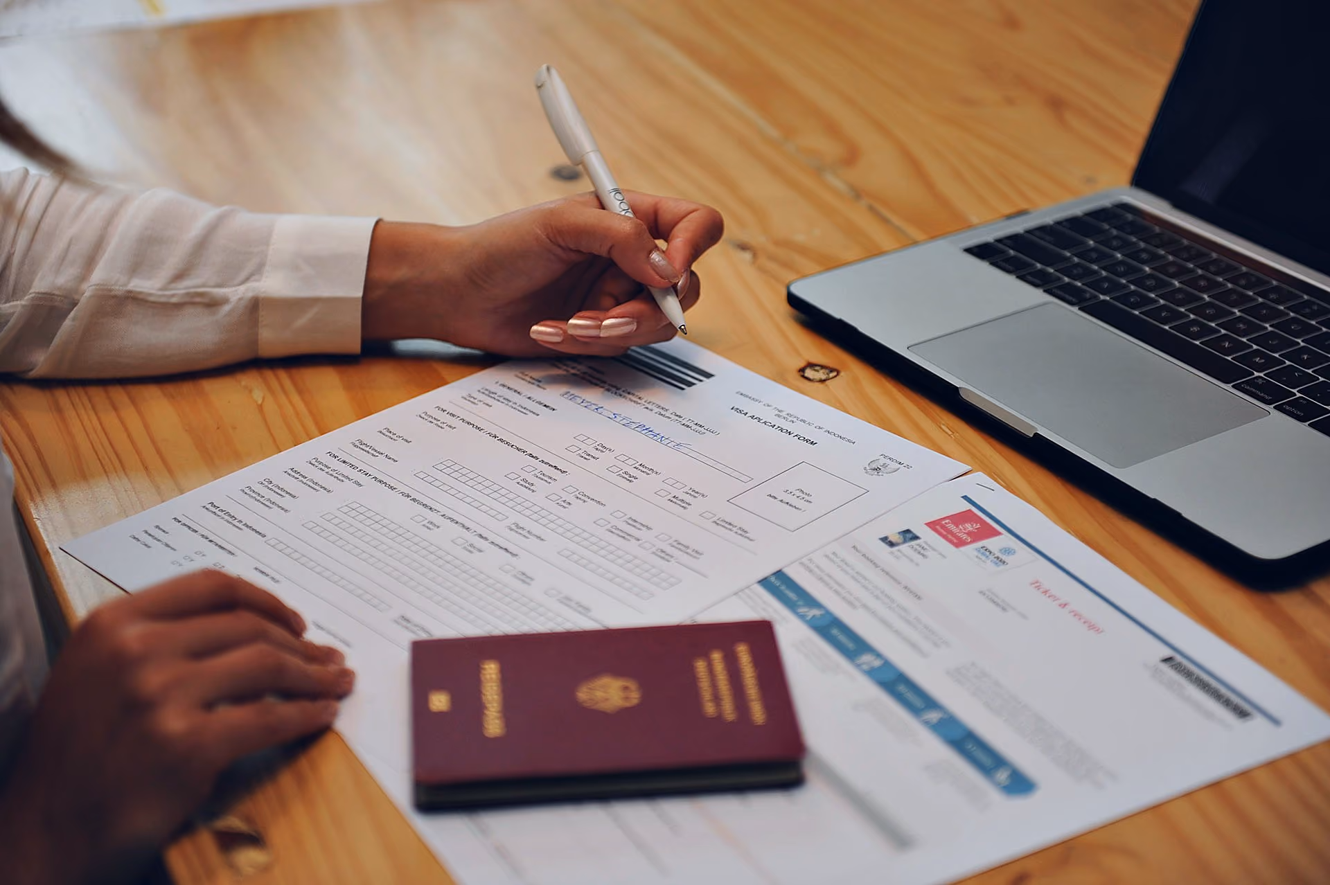 Student filling in visa documents for studying in Bali, with a passport on the table